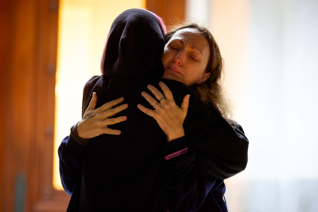 A close-up view of two people hugging each other as one of them tries.