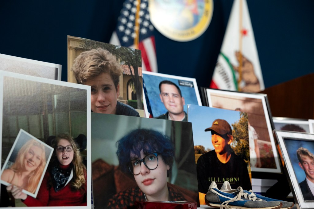 Several printed photographs of people are displayed upright on a table, with flags and a state seal visible in the background.
