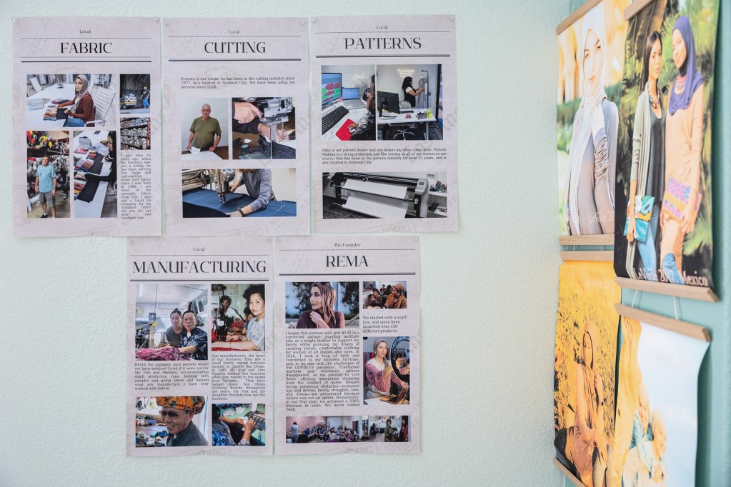 Newspaper graphics with text and photos hang on a light blue wall. The graphics show various production facts of a small business company, including fabric, cutting, patterns, and manufacturing details.