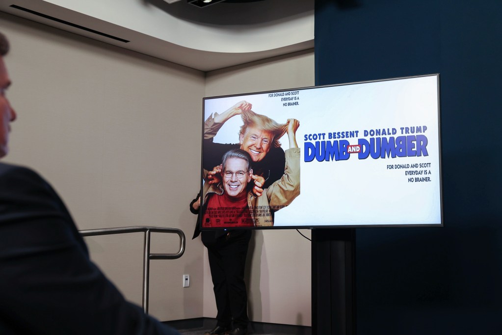 A graphic displayed on a monitor with a mocking the movie poster of "Dumb and Dumber" featuring U.S. President Donald Trump and U.S. Secretary of the Treasury Scott Bessent.