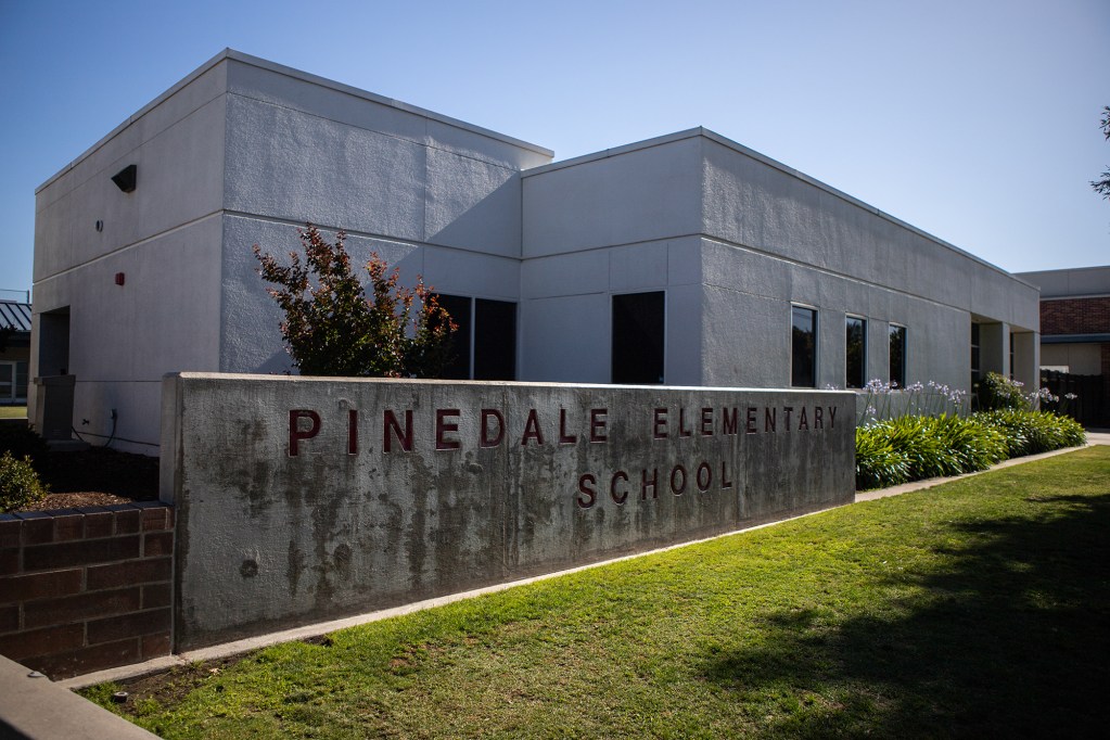 The exterior of a white building with a concrete sign on the front that reads "Pinedale Elementary School"